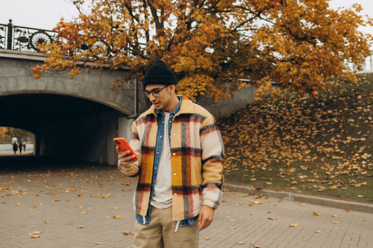 Jeune homme portant un bonnet parisien noir style streetwear dans un parc automnal urbain