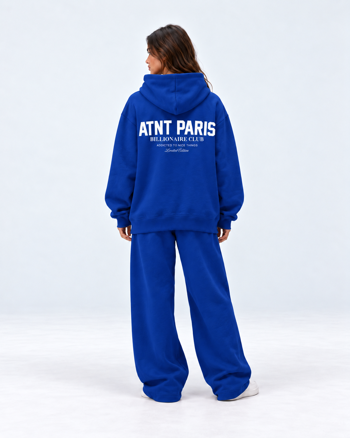 Sweat Billionaire Club bleu ATNT PARIS — porte dos tourne, studio gris clair