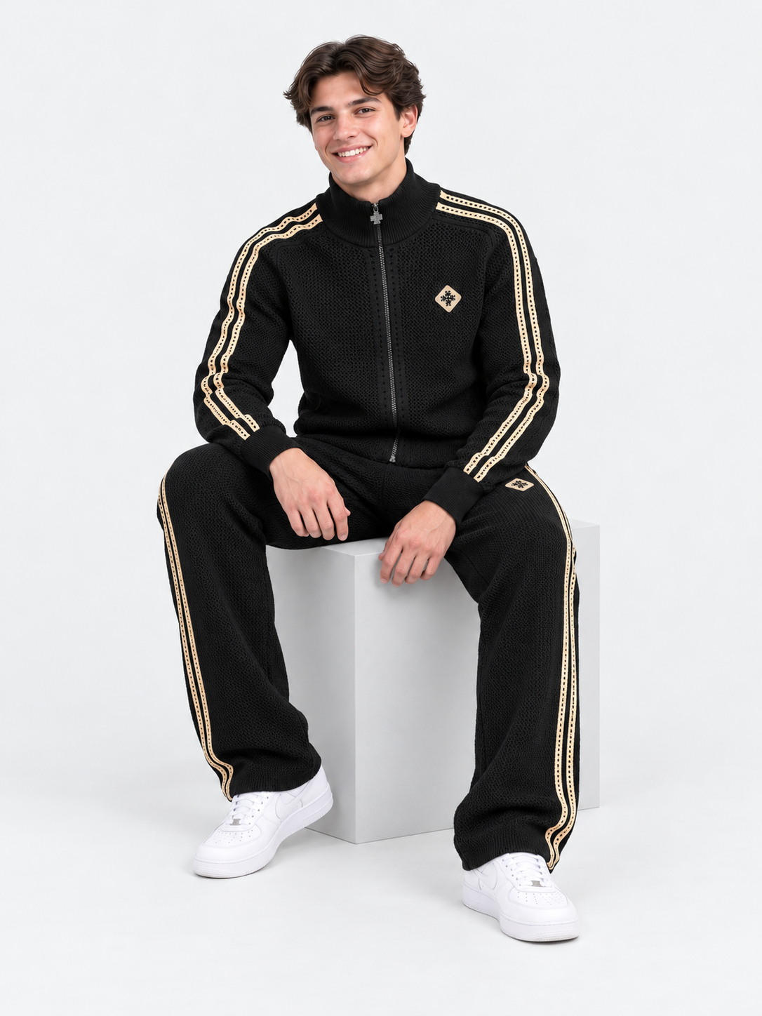 ATNT Tracksuits studio : Pantalon de Survêtement Signature Noir – Détail Crochet, vue assise sur fond gris clair