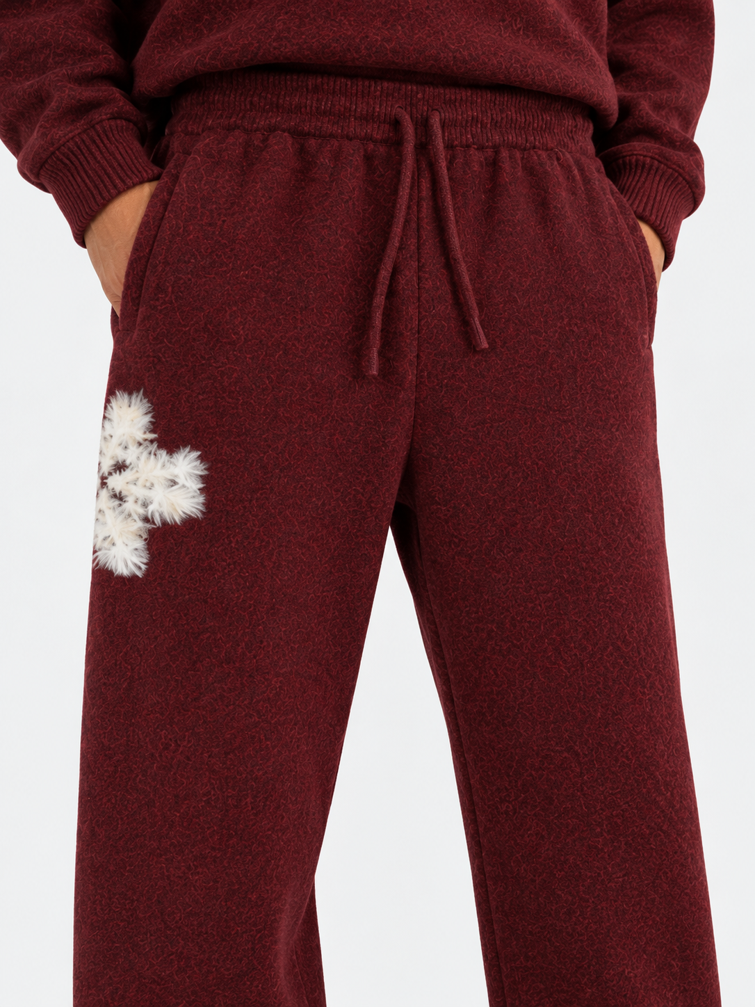 ATNT Tracksuits studio : Pantalon de jogging en maille fluffy monogramme signature bordeaux, détail de la matière sur fond gris clair