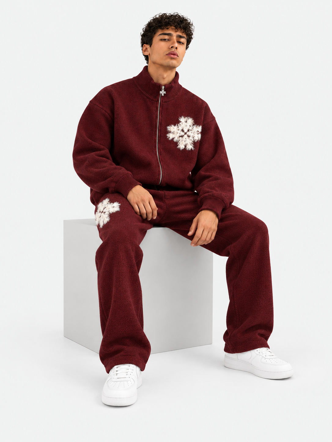 ATNT Tracksuits studio : Pantalon de jogging en maille fluffy monogramme signature bordeaux, vue assise sur fond gris clair