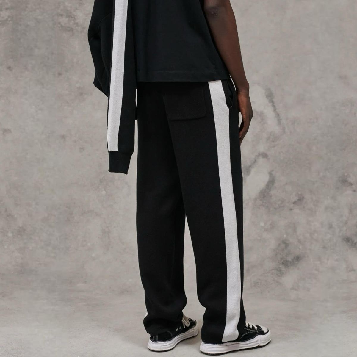 Pantalon knitted noir signature rayures latérales ATNT PARIS, porté, vue de profil.