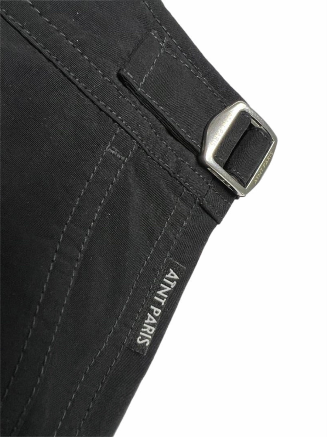 Short riviera noir ATNT PARIS, détail de la patte de réglage et de l’étiquette.