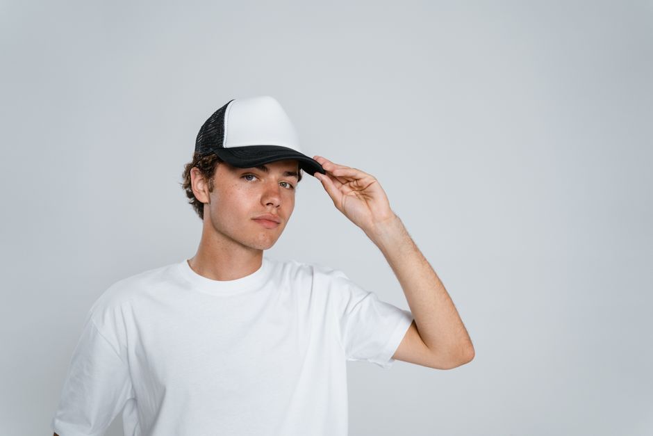 Jeune homme ajustant sa casquette blanche et noire, geste de mesure du tour de tête