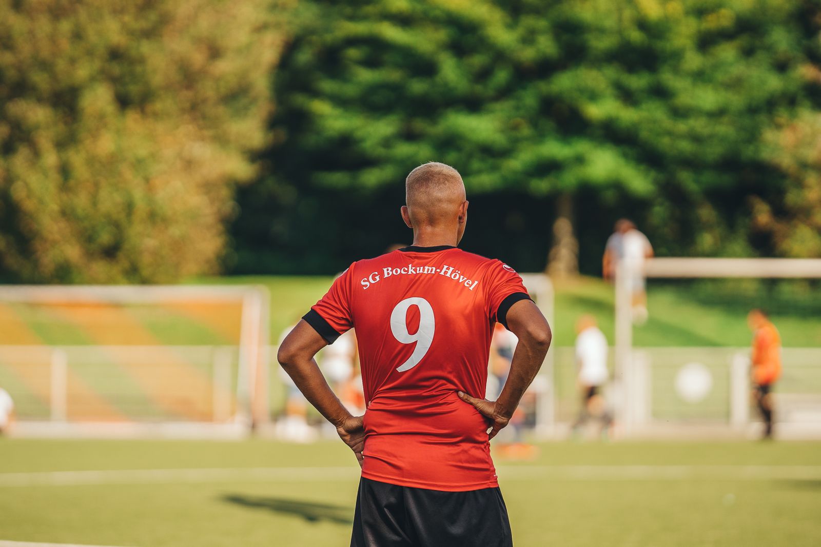 Joueur de football de dos en maillot rouge floqué du numéro 9 sur un terrain
