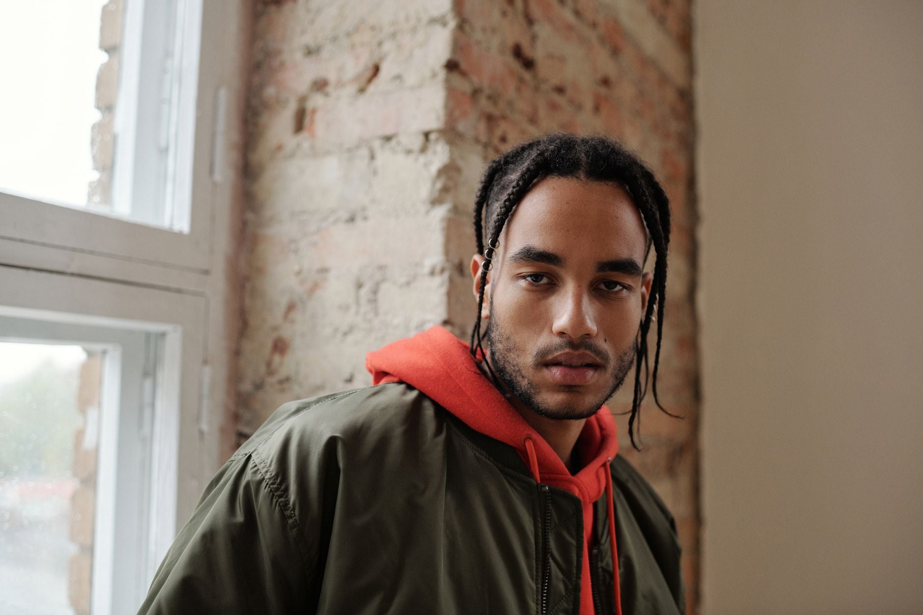 Jeune homme en veste bomber oversize kaki portée sur un sweat rouge, ambiance urbaine intérieure