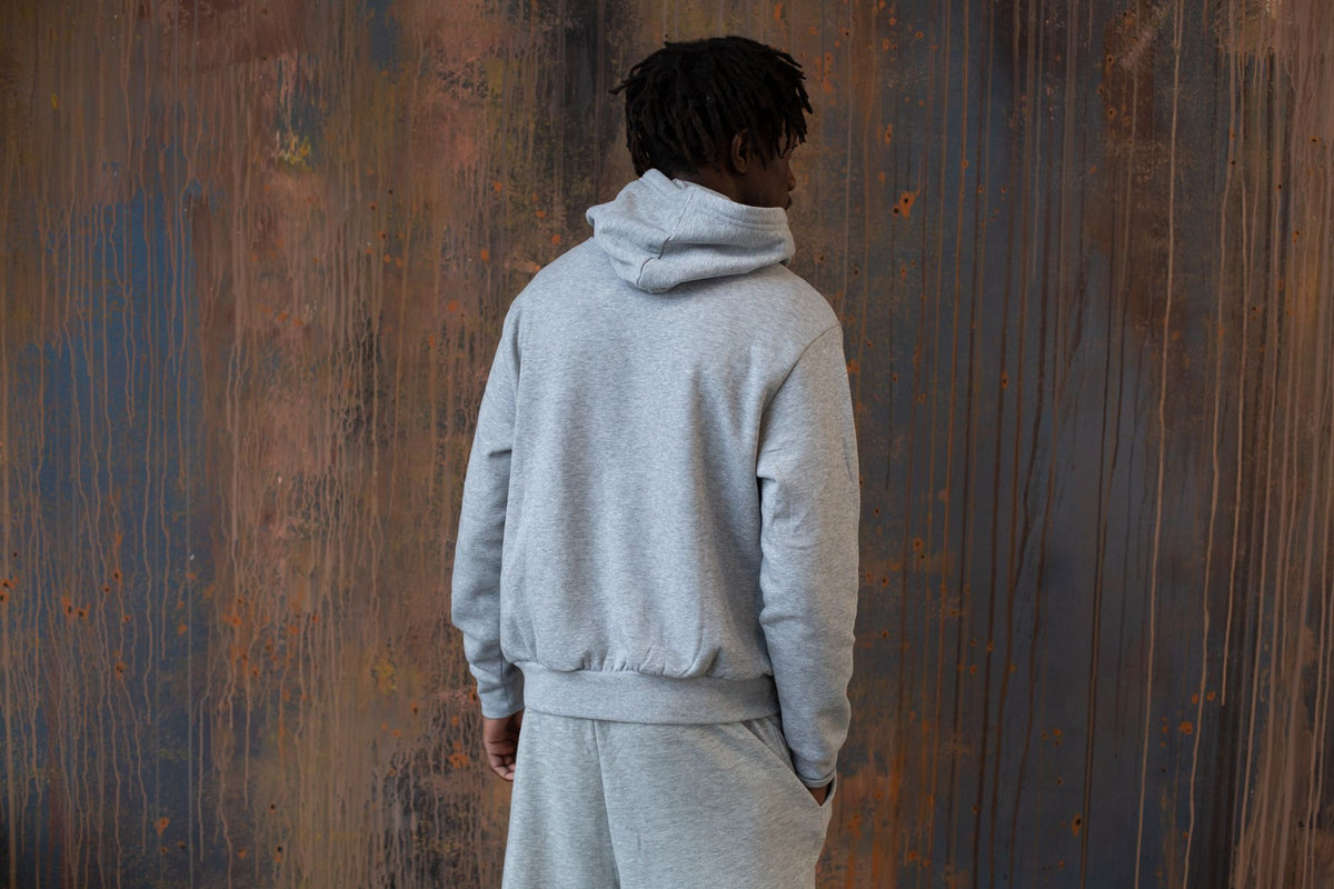 Homme en jogging gris coordonné vu de dos dans une ambiance urbaine industrielle