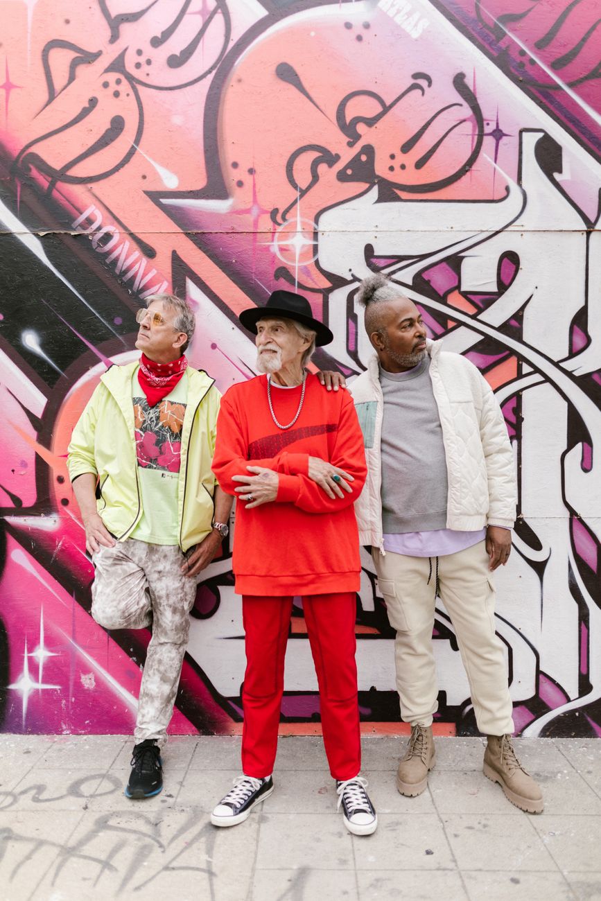 Association couleur vêtement homme : trois silhouettes streetwear en jaune, rouge et beige devant un mur graffé