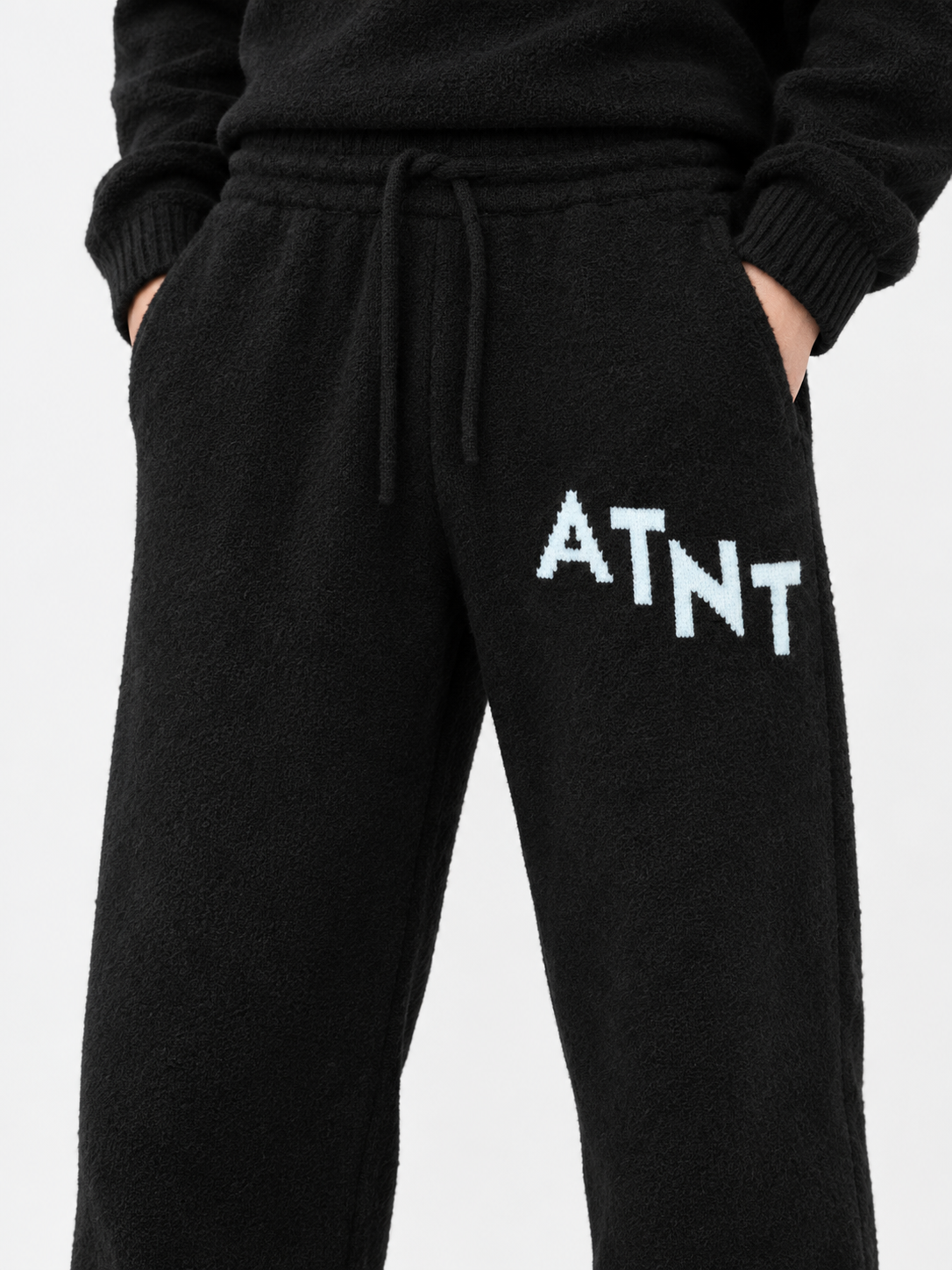 ATNT Tracksuits studio : Jogging Oversize Noir Effet Cachemire, détail de la matière sur fond gris clair