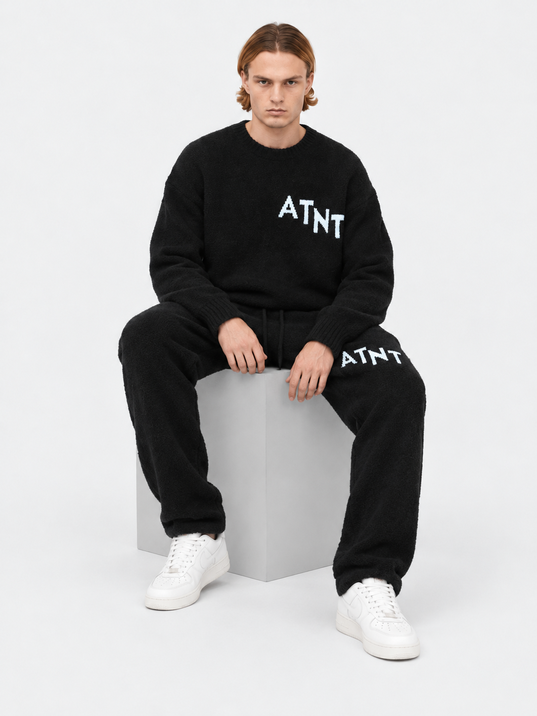 ATNT Tracksuits studio : Jogging Oversize Noir Effet Cachemire, vue assise sur fond gris clair